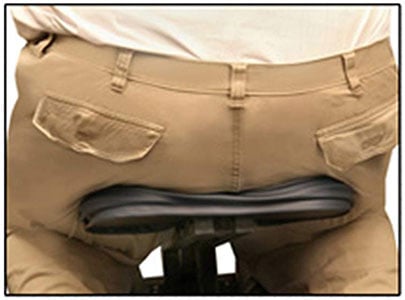 A cropped image of a person seated on a normal massage chair showing a narrower seat width vs. Apollo's seat width