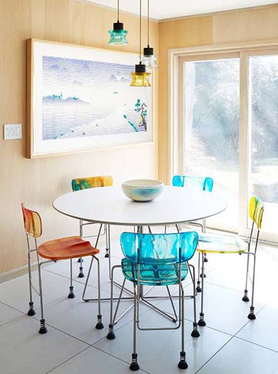 Five multicolored Broadway Chairs surround a white round dining table