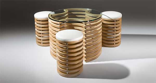 A cylindrical coffee table with a glass top that can house the three cylindrical wood stools with white seat cushion