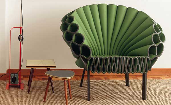 A green Peacock Chair with small side tables on the left