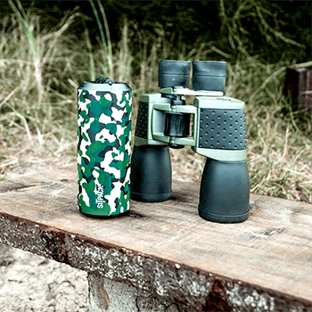 Sitpack 2 in black camo next to a binoculars on a wooden table